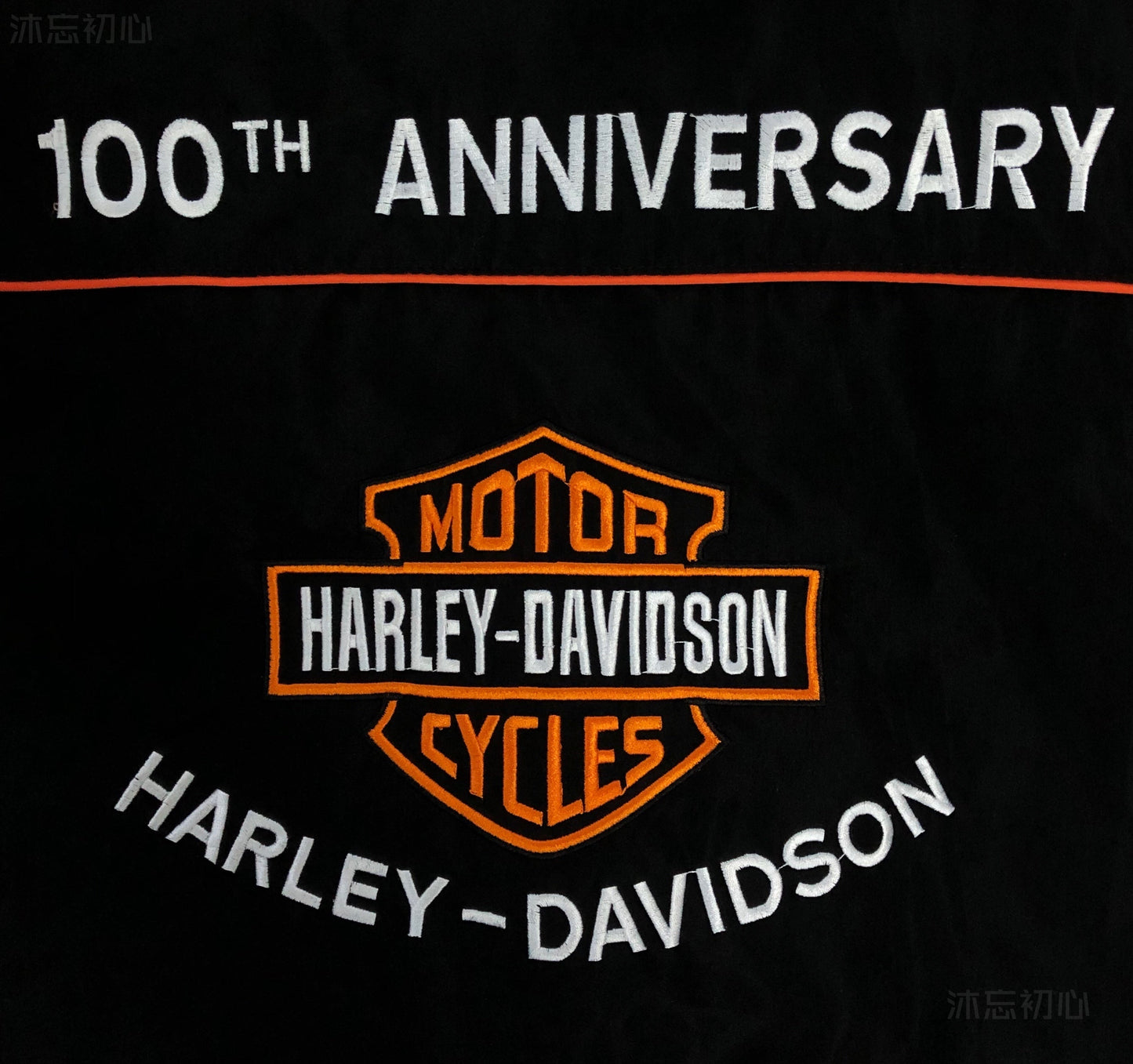 Vintage black Harley-Davidson jacket with embroidered logos and orange accents.