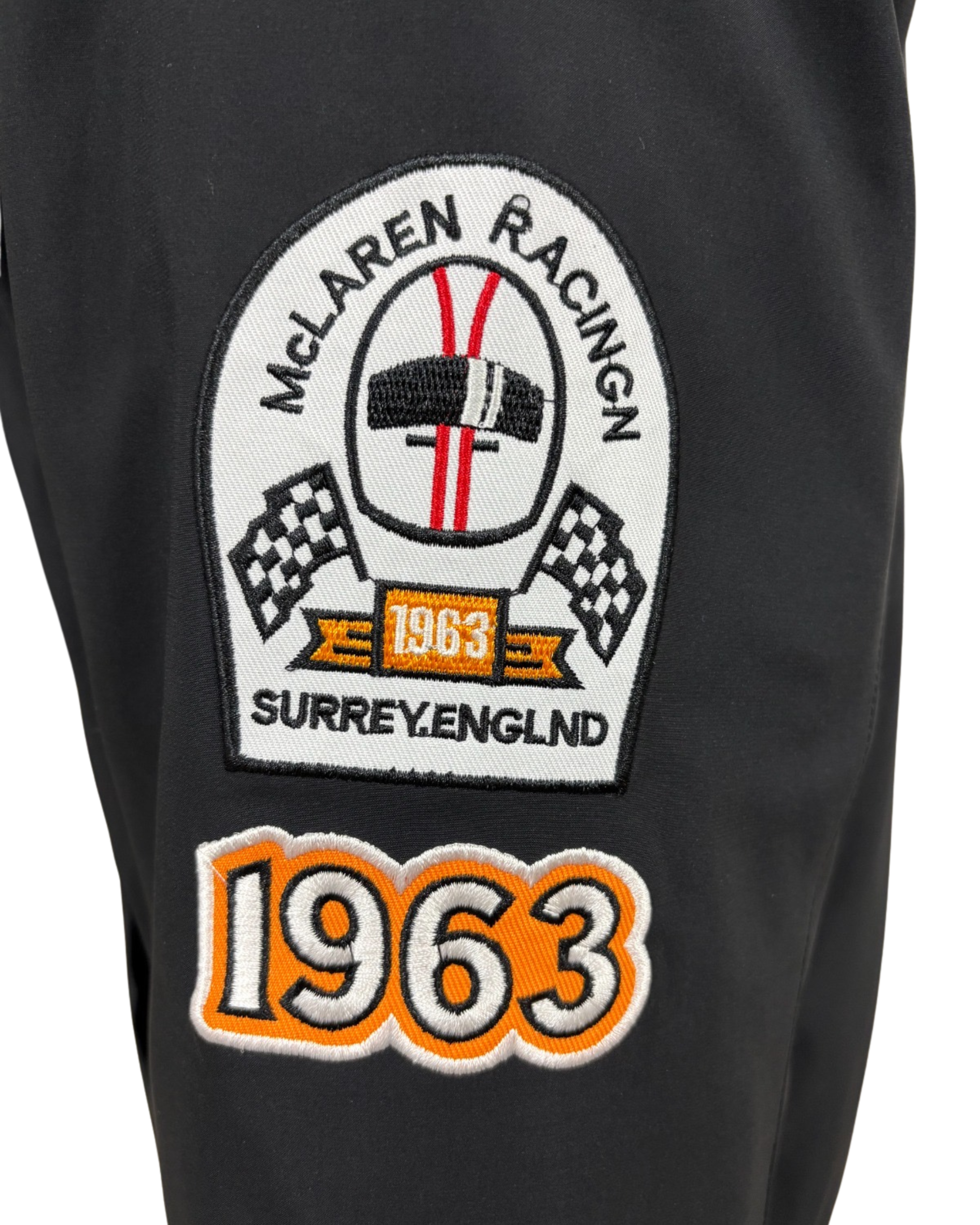 Close-up of McLaren black racing jacket chest logo and orange sponsor patch detail